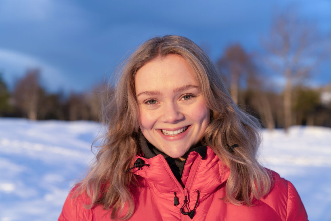 Ane Kvistad har på seg en rød boblejakke og smiler kjempesøtt ute i snøen.