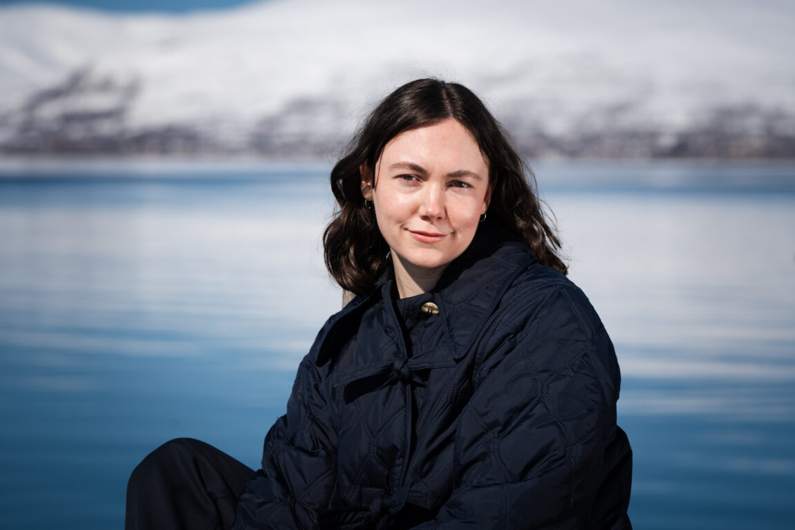 Stéphanie Turcotte sitter på en brygge ved vannet og smiler forsiktig.
