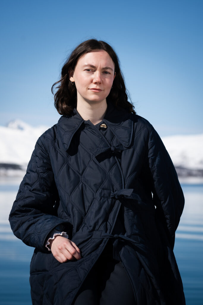 Stéphanie Turcotte står foran fjorden i Tromsø med en blå jakke og mørkt hår.