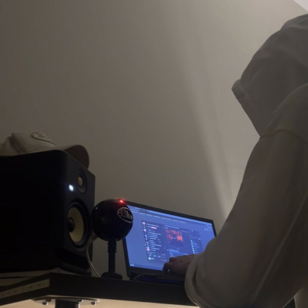 Sigurd K har på seg en grå hettegenser og jobber på en pc. Vi ser bare ryggens hans mens han jobber.