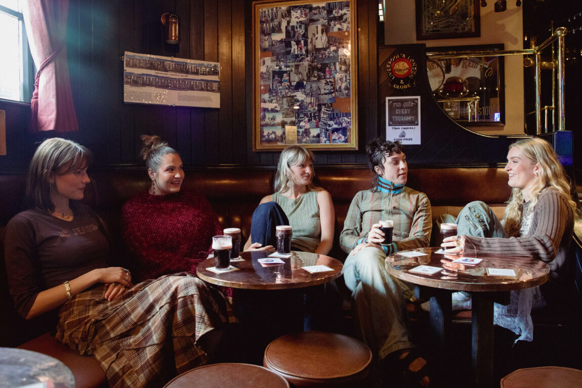 Girl Group sotter på en pub med hver sin Guinness. De prater og diskuterer seg i mellom. 