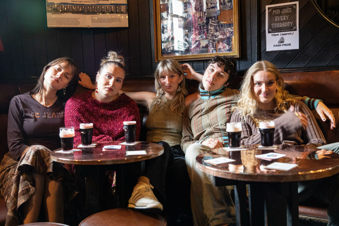 Girl Group sitter med hver sin Guiness og poserer i en bar gruppe.
