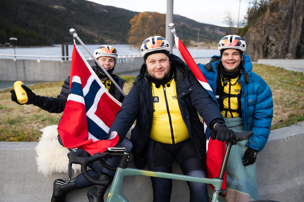 Anna, Jonas og Sindre gliser i kamera med norske flagg mellom seg