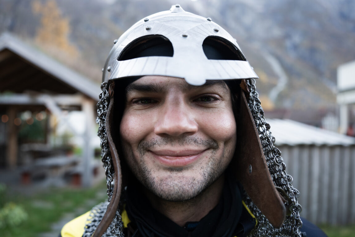 Sindre kikker lurt inn i et vidvinkel kamera med vikinghjelm og brynje rundt hodet.