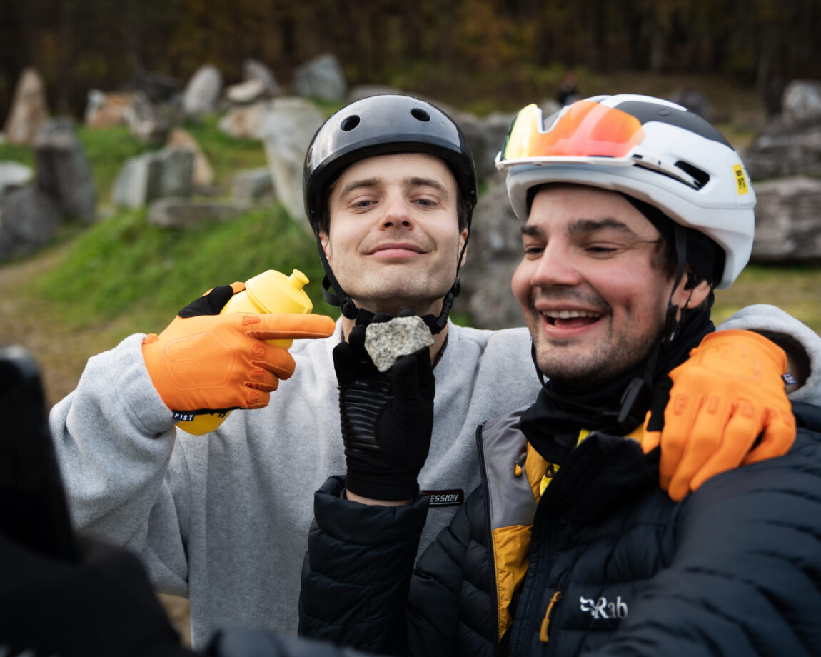 Sindre holder en stein og trener Eirik peker mot den.