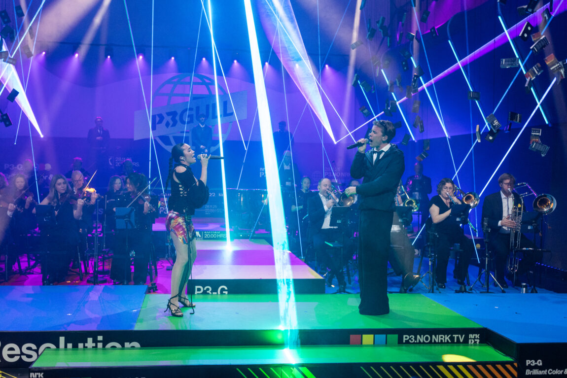 To stykker står på scenen, bak dem sitter kork og spiller.